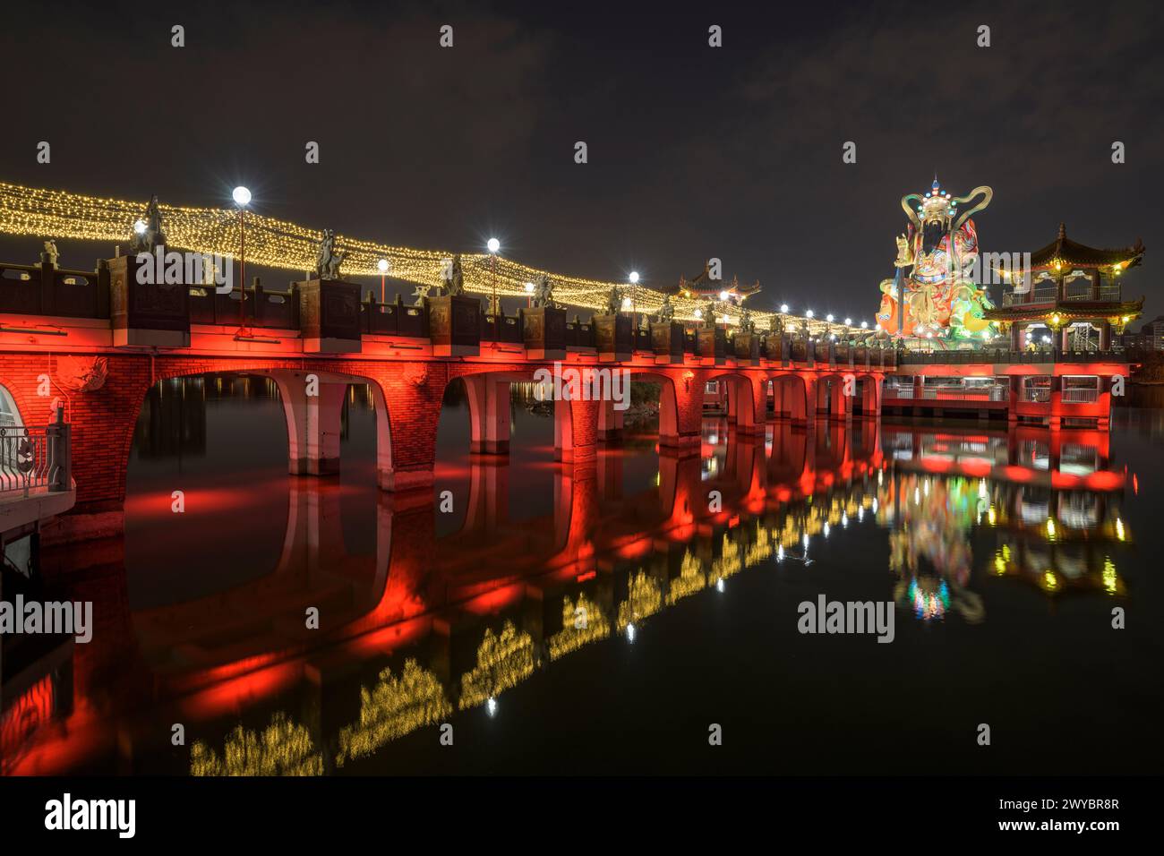 Eine Langzeitaufnahme einer hell dekorierten Zuoying Yuandi Tempelbrücke und ihre Reflexionen auf dem Zuoying Lotus Teich bei Nacht Stockfoto
