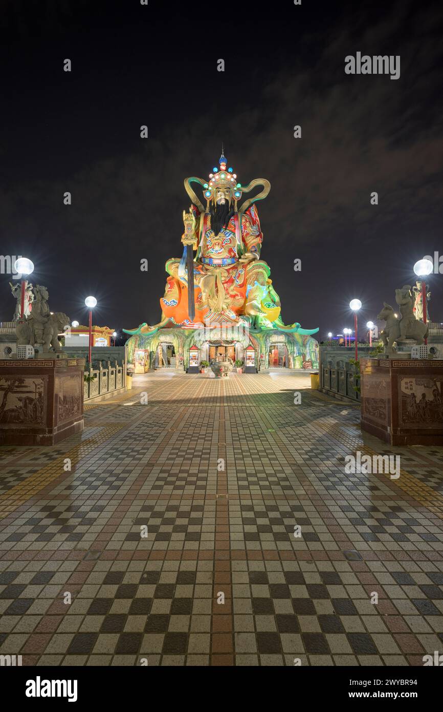 Eine blendende Ausstellung von beleuchteten Lichtern über einer geschmückten Brücke, flankiert von mythologischen Statuen, die zum Zuoying Yuandi Tempel führen, der sich vor der Dunkelheit der Nacht befindet Stockfoto