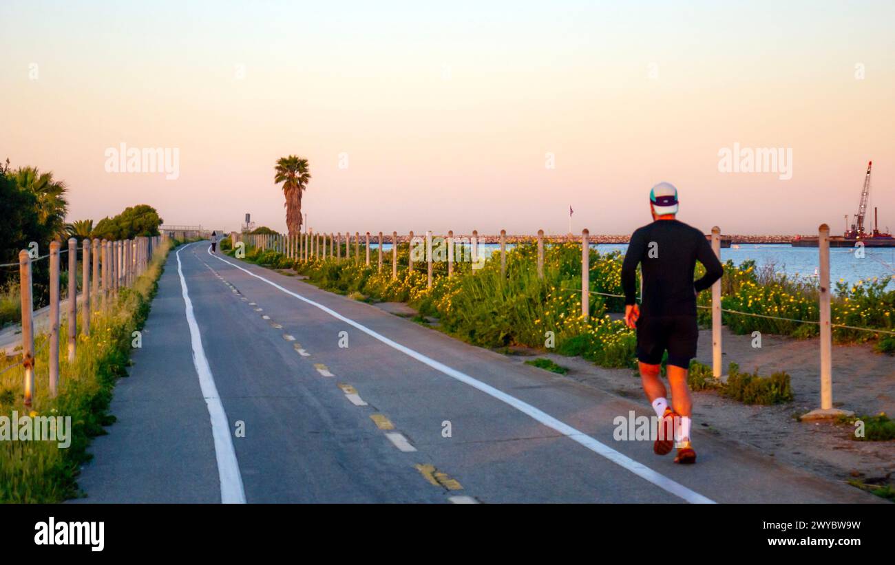 Ein Mann, der bei Sonnenaufgang auf einem Joggingpfad in Marina del Rey, Kalifornien, USA läuft. Gesunde Gewohnheiten, Laufen für Fitness, Bewegung am Morgen Stockfoto