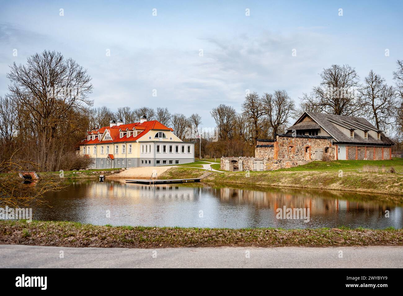 Blick auf Berkenes Manor und landwirtschaftliche Gebäude. Gelegen an einem malerischen Ort im frühen Frühling. Lettland, Baltikum. Stockfoto