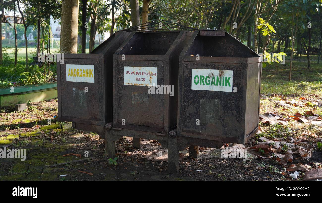 Ein rostiger Abfallbehälter in einem Park, der in drei Abfallkategorien unterteilt ist: Anorganischer Abfall, B3-Abfall und organischer Abfall Stockfoto