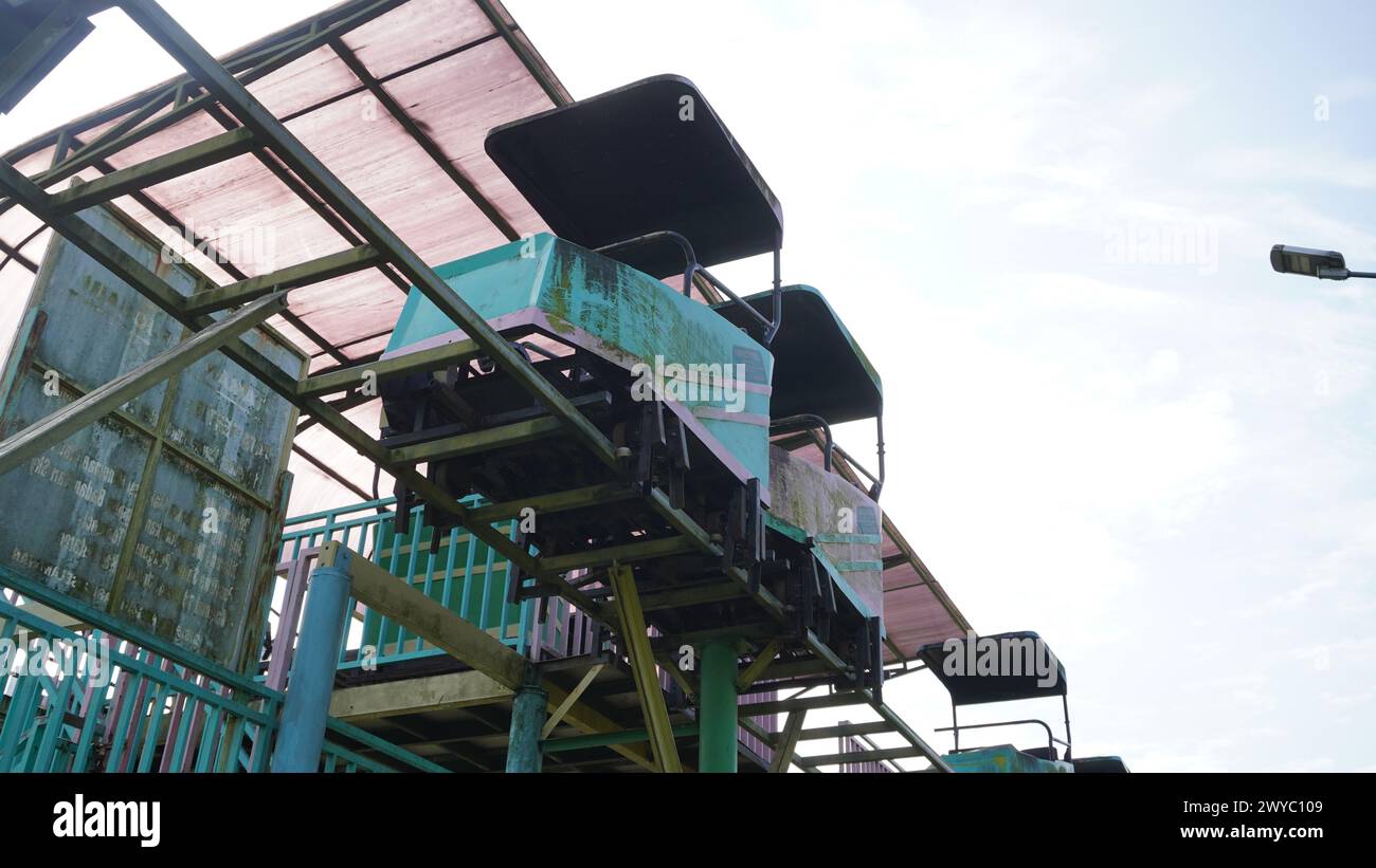 Sky-Bike-Touren in Taman Singha Malang, die seit langem nicht mehr in Betrieb sind und nicht mehr funktionieren. Der Zug und die Schienen sehen ebenfalls rostig aus Stockfoto