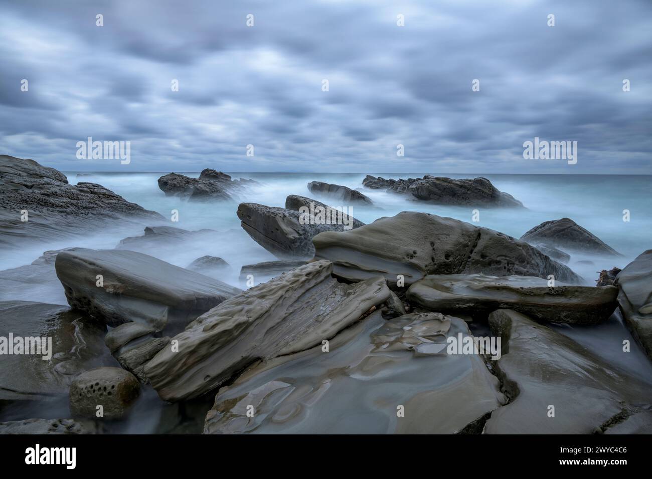 Mystische Atmosphäre mit glatten, verwitterten Felsen an einer rauen Küste, unter einem bewölkten Himmel Stockfoto