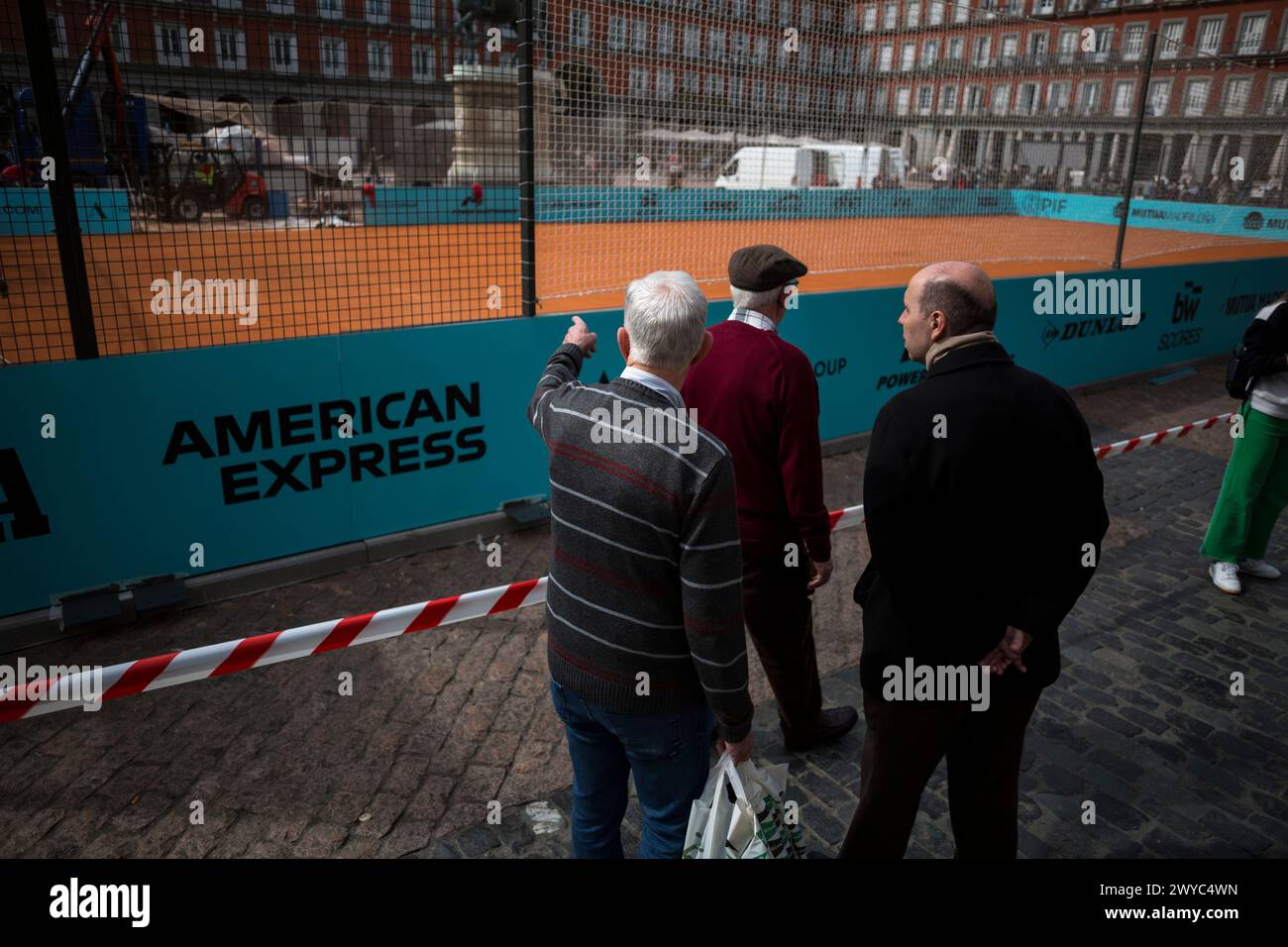 Madrid, Spanien. April 2024. Drei ältere Menschen beobachten einen Tennisplatz auf der Plaza Mayor von Madrid. Auf dem Plaza Mayor in Madrid wird ein Tennisplatz eingerichtet, um das Turnier Mutua Madrid Open 2024 zu fördern, an dem die besten Tennisspieler der Welt teilnehmen, das vom 22. April bis 5. Mai in Madrid im Caja Magica stattfindet. Quelle: SOPA Images Limited/Alamy Live News Stockfoto