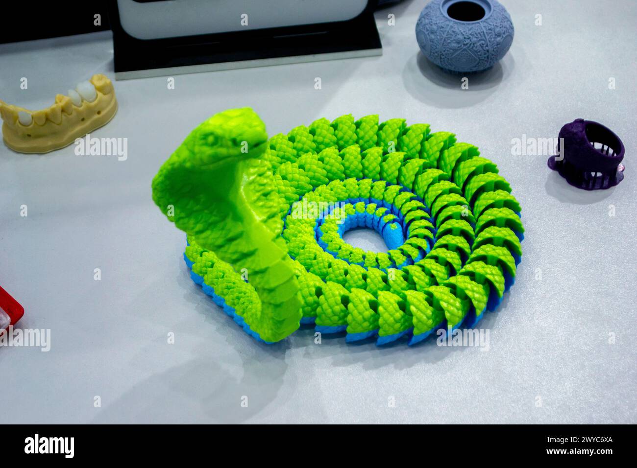 Grünes Schlangenspielzeugmodell, gedruckt auf einem 3D-Drucker aus geschmolzenem Kunststoff. Vom 3D-Drucker erzeugtes Objekt in Schlangenform. Detaillierter grüner Prototyp auf 3D-Drucker in Nahaufnahme gedruckt. Neue moderne Additivtechnologien Stockfoto