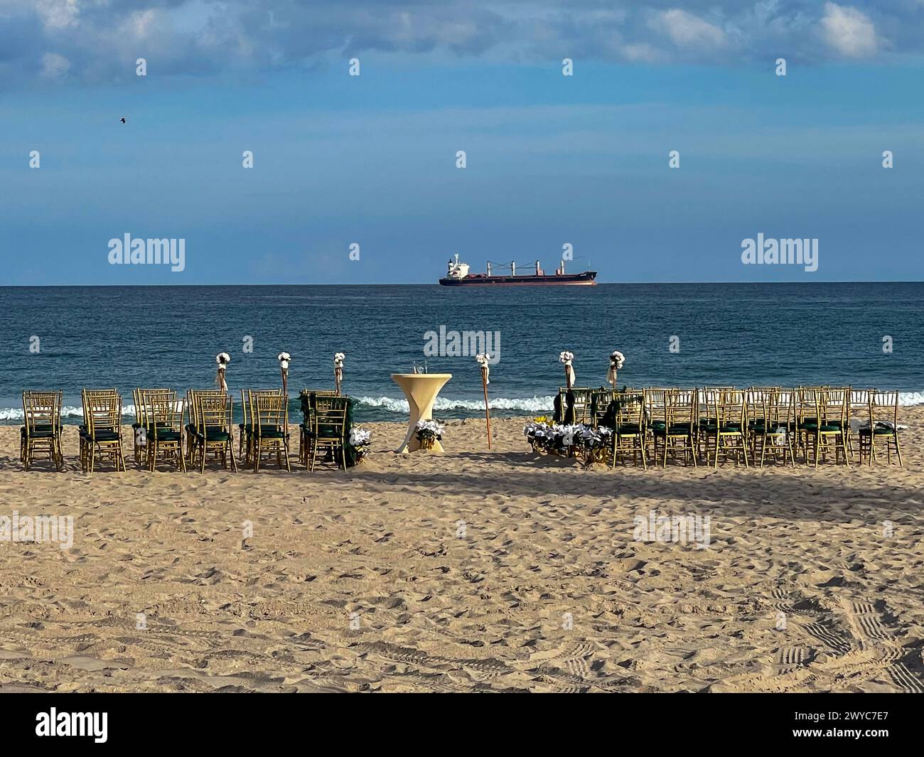 Leere Stühle und Blumenarrangements werden für eine Hochzeit am Strand in Südflorida eingerichtet. Stockfoto