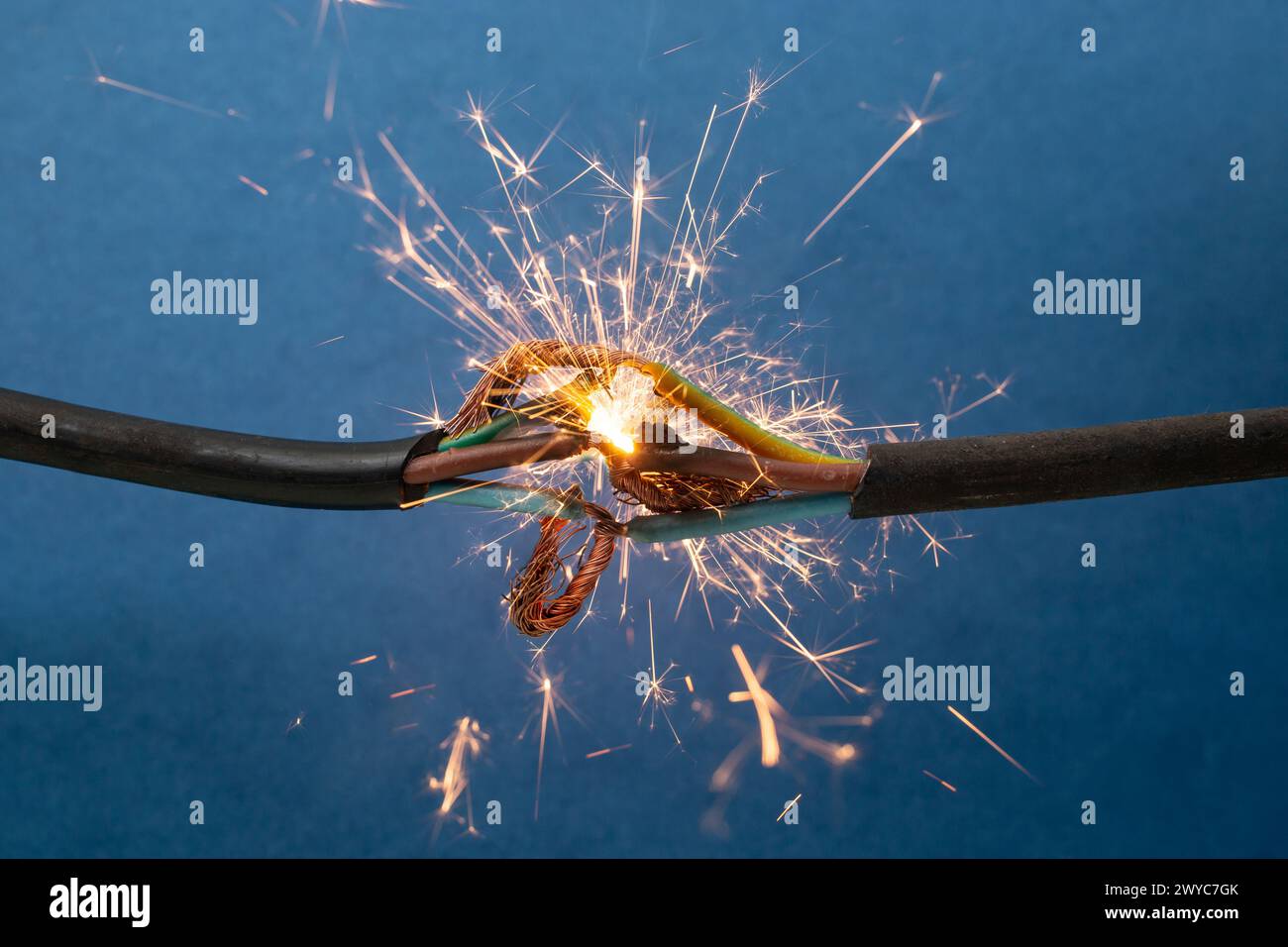 Funkenexplosion zwischen elektrischen Kabeln, auf blauem Hintergrund, Brandschutzkonzept Stockfoto