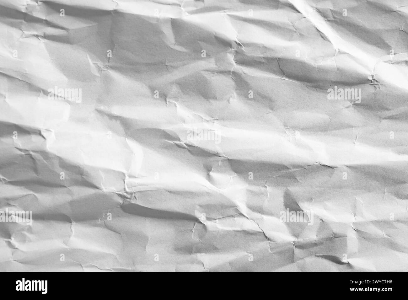 Weißes Papier mit schattigen Falten, weicher Fokus in Nahaufnahme, abstrakte Textur Stockfoto