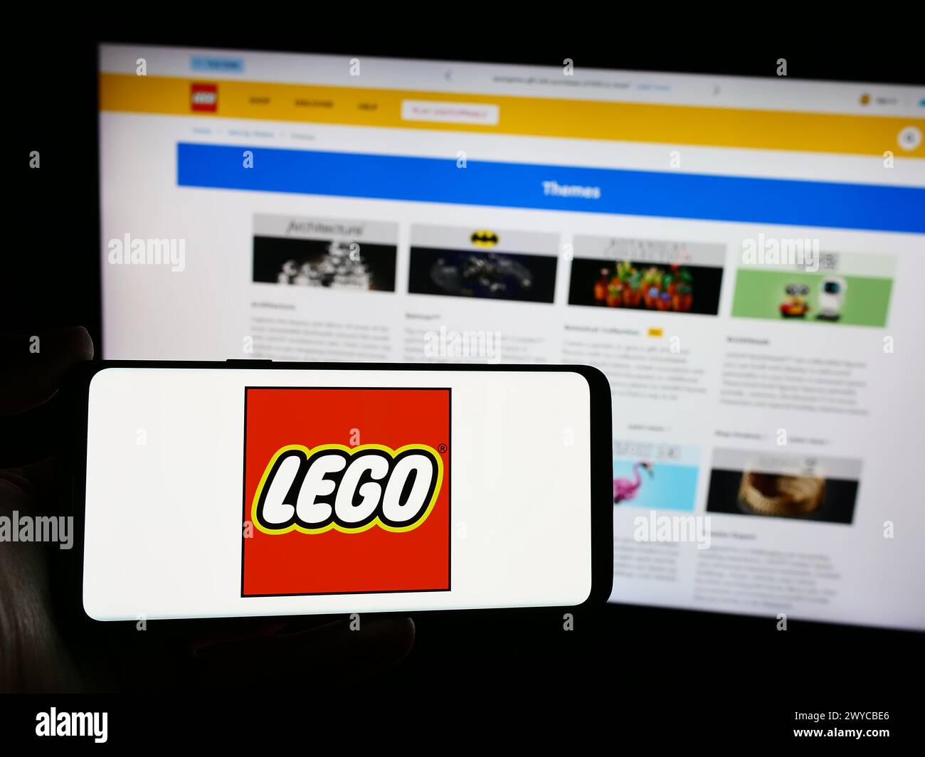 Person mit Smartphone mit Logo des dänischen Bauspielzeugherstellers LEGO WIE vor der Website. Schwerpunkt auf dem Display des Telefons. Stockfoto