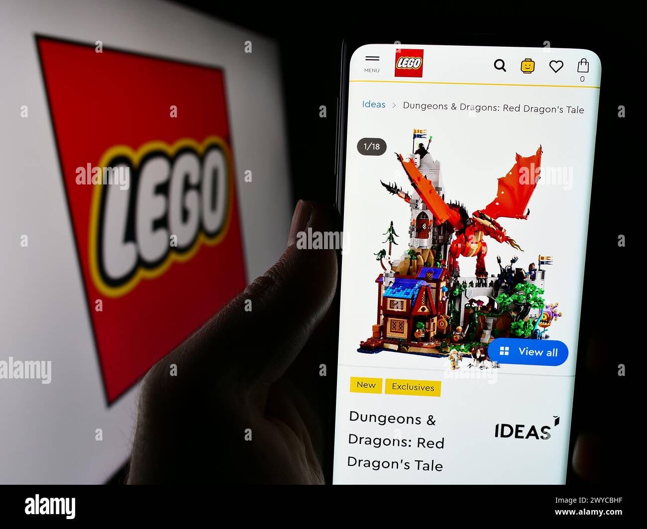 Person, die ein Mobiltelefon mit der Webseite des dänischen Bauspielzeugherstellers LEGO vor dem Firmenlogo hält. Konzentrieren Sie sich auf die Mitte des Telefondisplays. Stockfoto