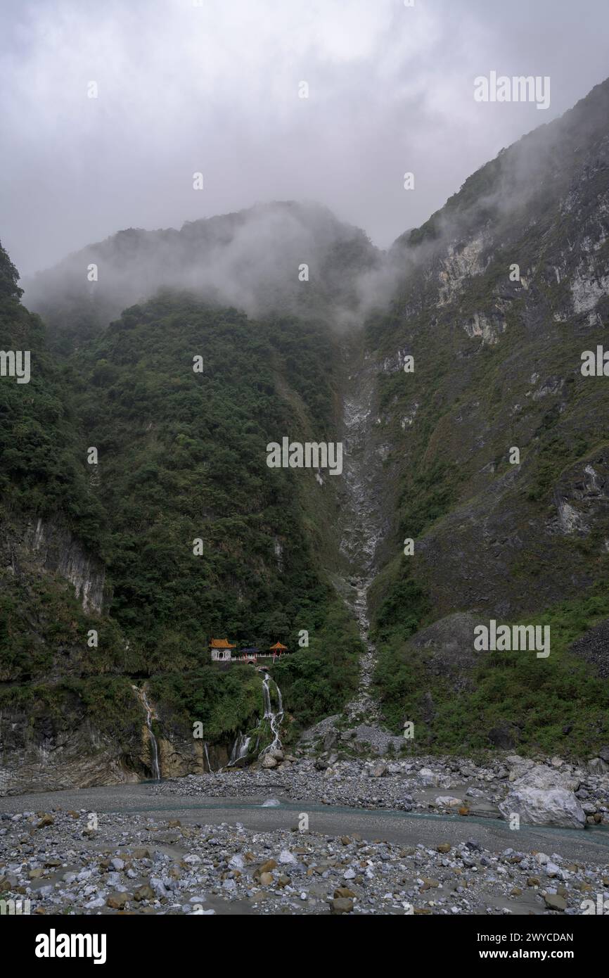 Ein stimmungsvoller, ätherischer Blick auf eine nebelige Bergschlucht mit einem sanften Fluss, der sich seinen Weg windet Stockfoto