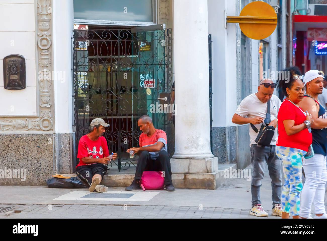 Zwei kubanische Männer trinken Alkohol vor der Haustür des Gebäudes, andere Menschen Lebensstil, in Havanna, Kuba Stockfoto