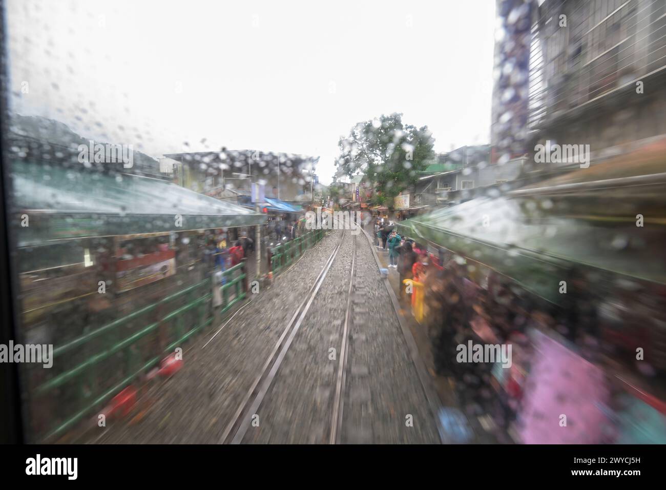 Eine lebendige und abstrakte Darstellung der Reise eines Zuges, die durch Bewegungsunschärfe an einem regnerischen Tag erfasst wird und Geschwindigkeit und Bewegung vermittelt Stockfoto