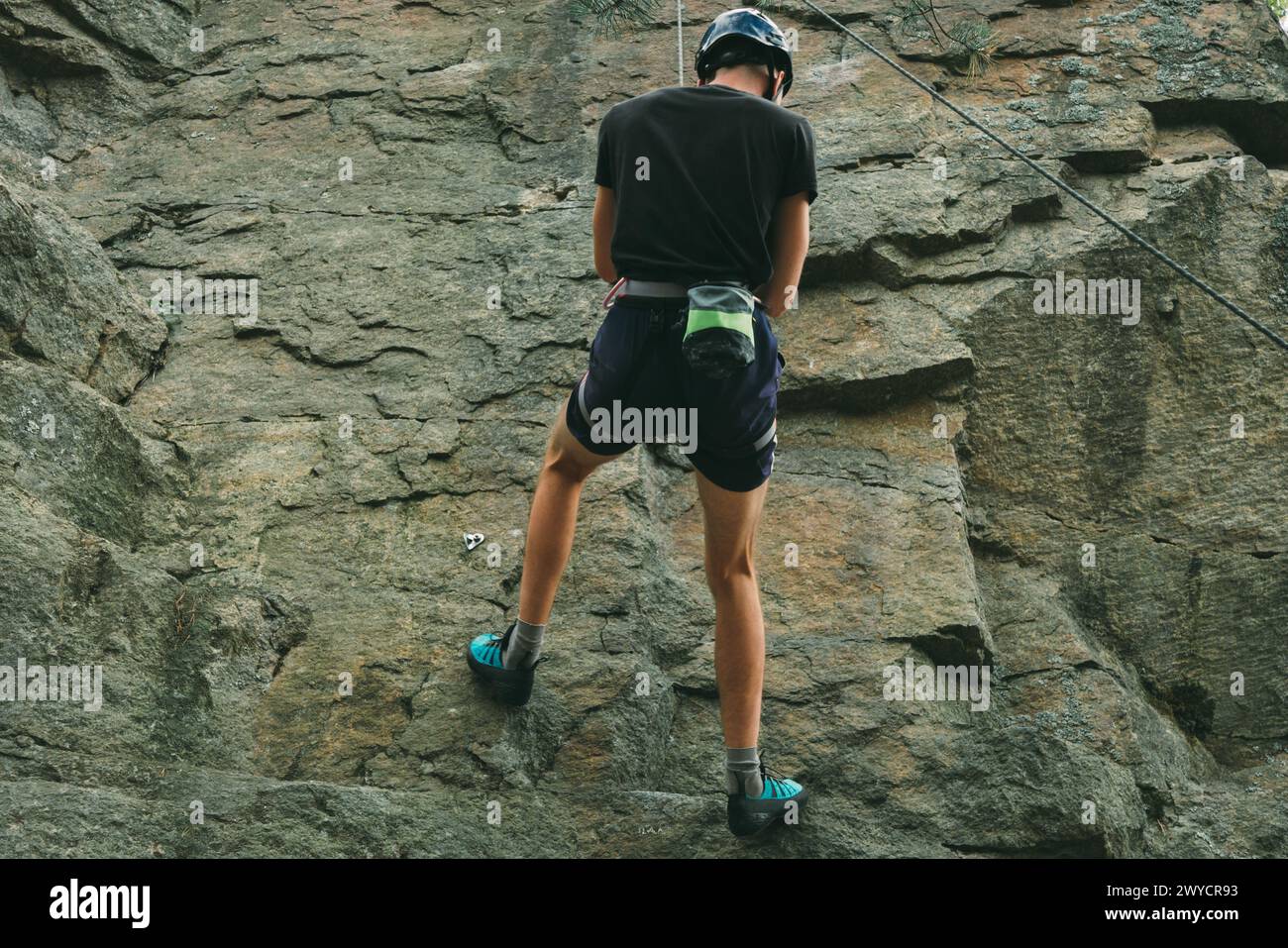 Junger Mann in Ausrüstung, der draußen klettert. Trainingsbereich für Outdoor-Aktivitäten. Extremsport. Stockfoto