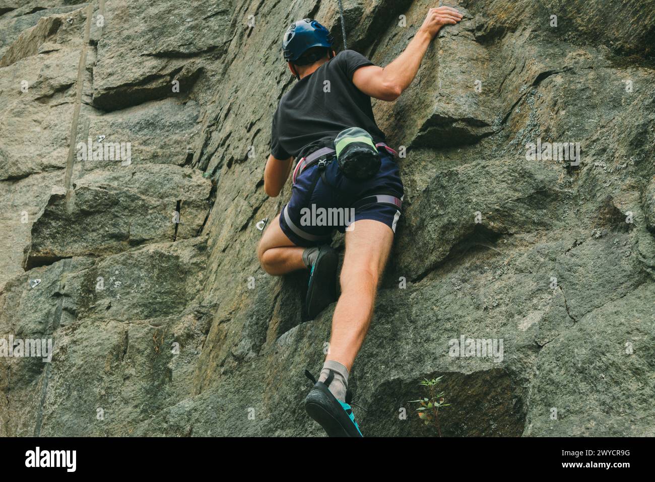 Junger Mann in Ausrüstung, der draußen klettert. Trainingsbereich für Outdoor-Aktivitäten. Extremsport. Stockfoto