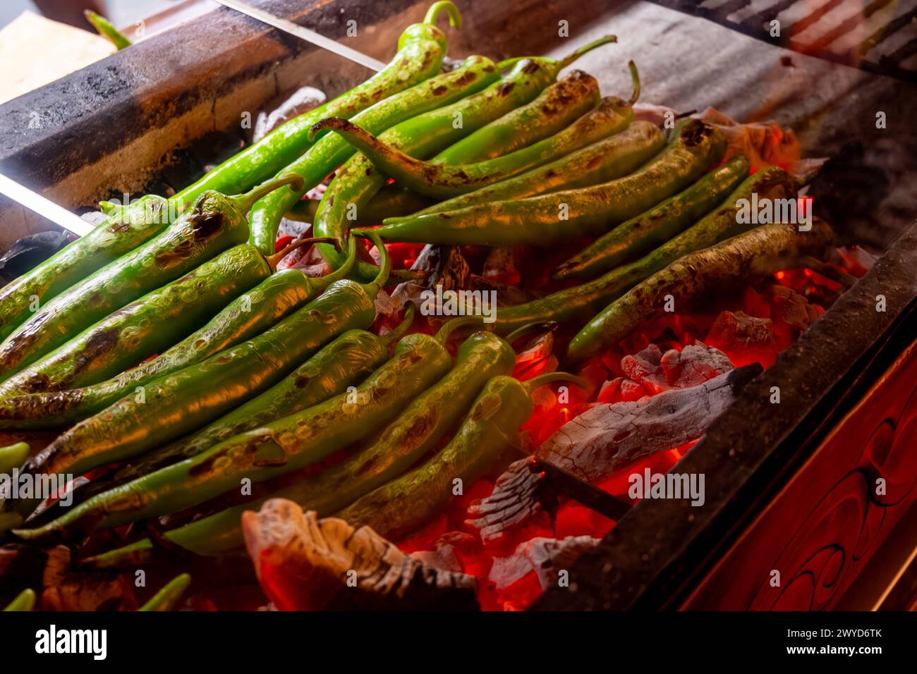 Barbecue mit grüner türkischer Paprika auf geflammtem Holzkohlegrill im türkischen Restaurant Stockfoto