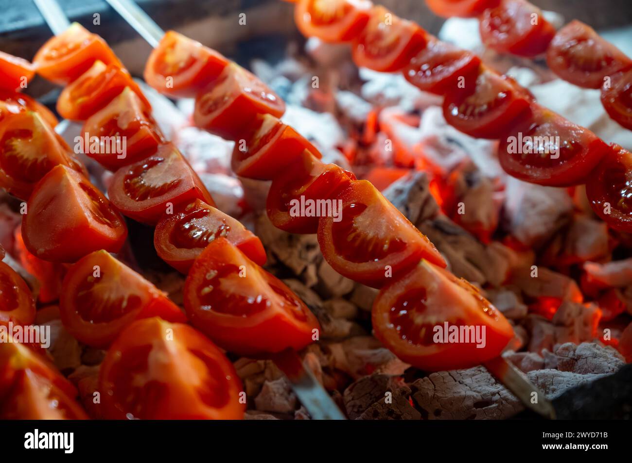Barbecue mit Reifen roten Tomaten auf geflammtem Holzkohlegrill im türkischen Restaurant Stockfoto