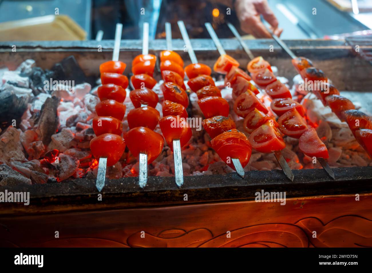 Barbecue mit Reifen roten Tomaten auf geflammtem Holzkohlegrill im türkischen Restaurant Stockfoto
