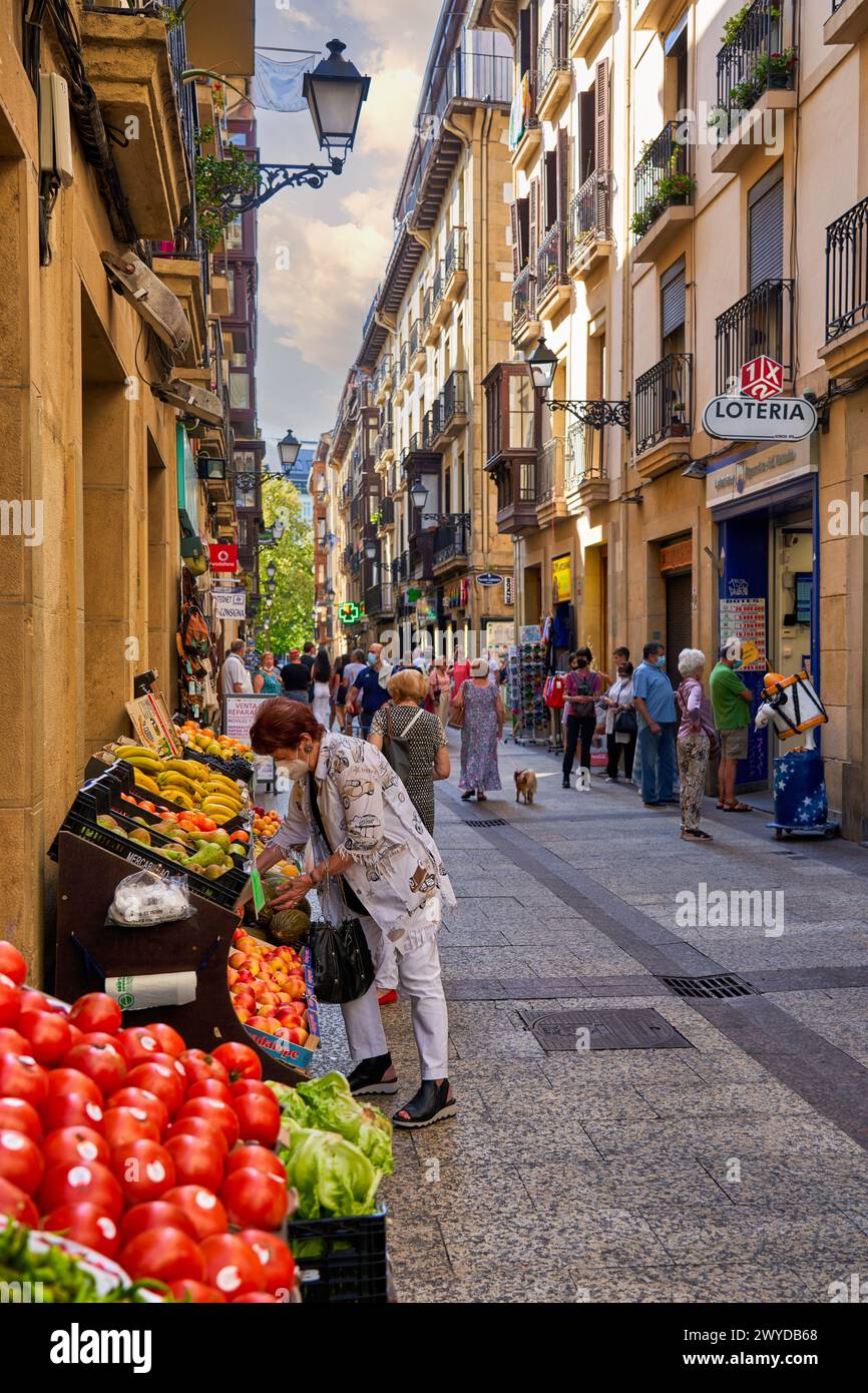 Mujer comprando en frutería de la parte Vieja, Donostia, San Sebastián, Gipuzkoa, País Vasco, España, Europa, Adentrarse en la parte Vieja es conocer el verdadero centro Social de Donostia, sus calles empedradas como la del 31 de Agosto, que conmemora el Incendio ese día de 1813, están llenas de bares para disfrutar de los mejores pintxos de la ciudad, y sus edificios emblemáticos como la Basílica de Santa María del Coro y la iglesia de San Vicente Son de gran atractivo e interés,. Stockfoto