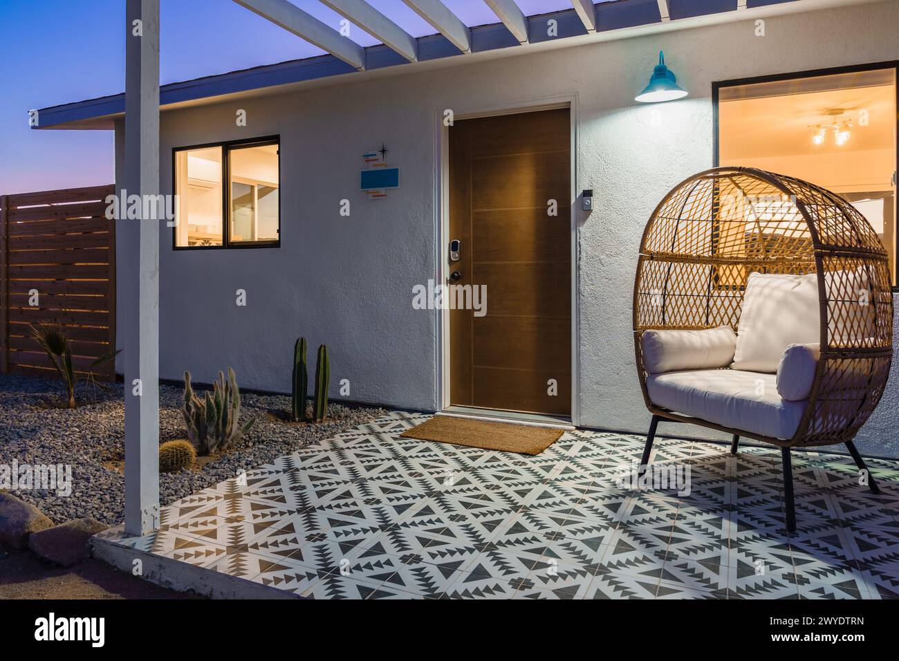Moderne Bohème Wüstenhaus Veranda mit Fliesen und Rattanstuhl in der Abenddämmerung Stockfoto