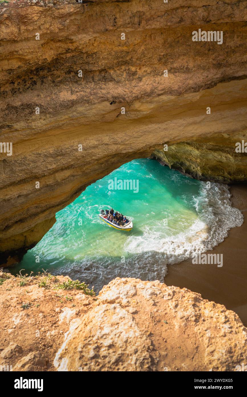 Touristen in einem Boot erkunden das türkisfarbene Wasser in der Benagil-Höhle in der Algarve, Portugal. Stockfoto