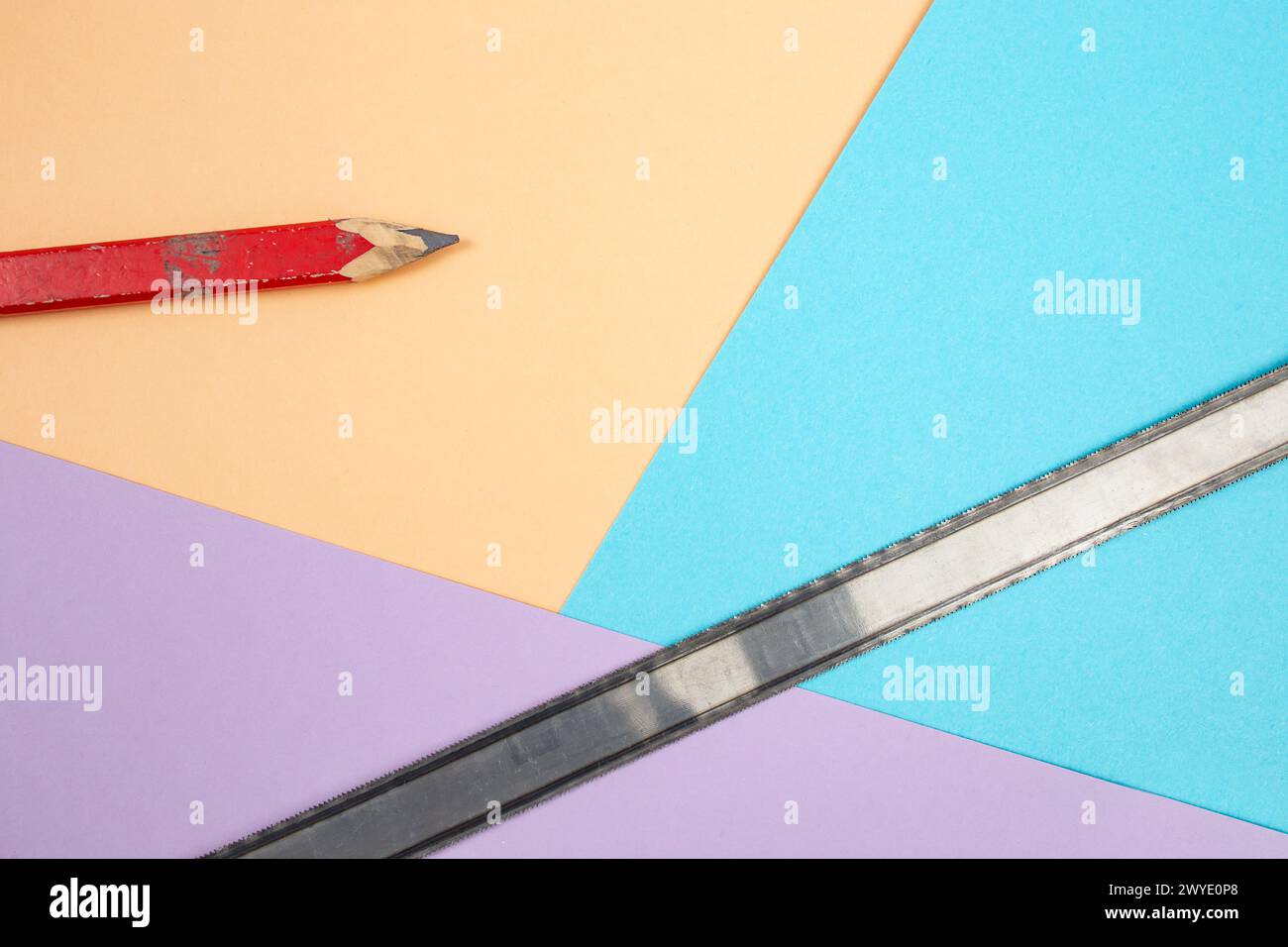 Roter Stift der Zimmerei mit einem Sägeblatt aus Metall auf farbigem Hintergrund Stockfoto