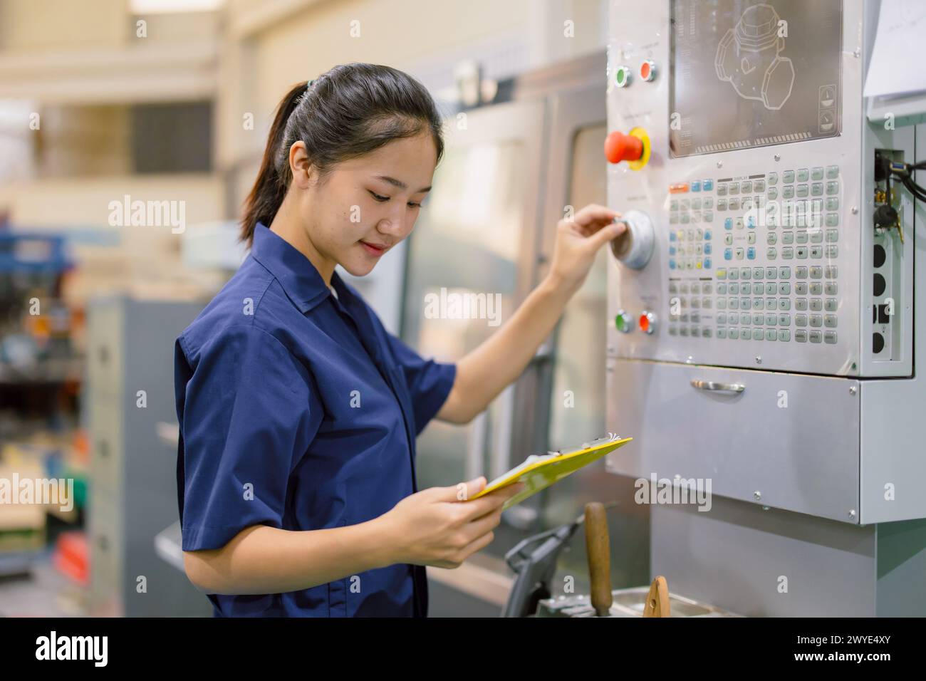 Ingenieurinnen steuern CNC-Industriemaschinen in der Metallproduktionswerkstatt. Asiatische junge Industriearbeiterin. Stockfoto