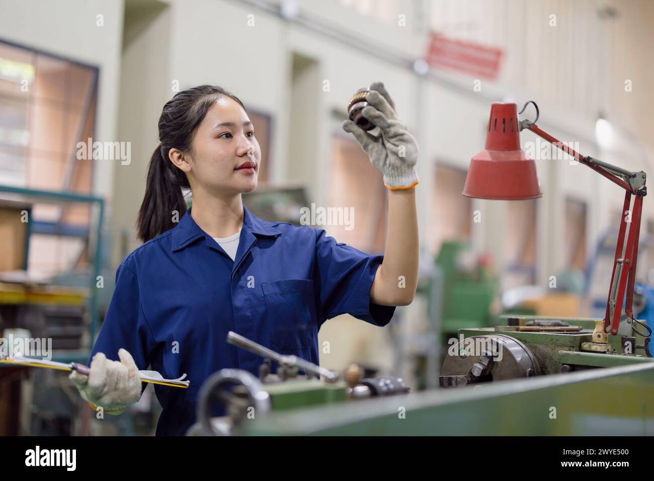 Asiatische Arbeiterinnen arbeiten in der Schwerindustrie mit CNC-Drehmaschine Fräsen Metallmaschine in Stahlproduktfabrik Stockfoto