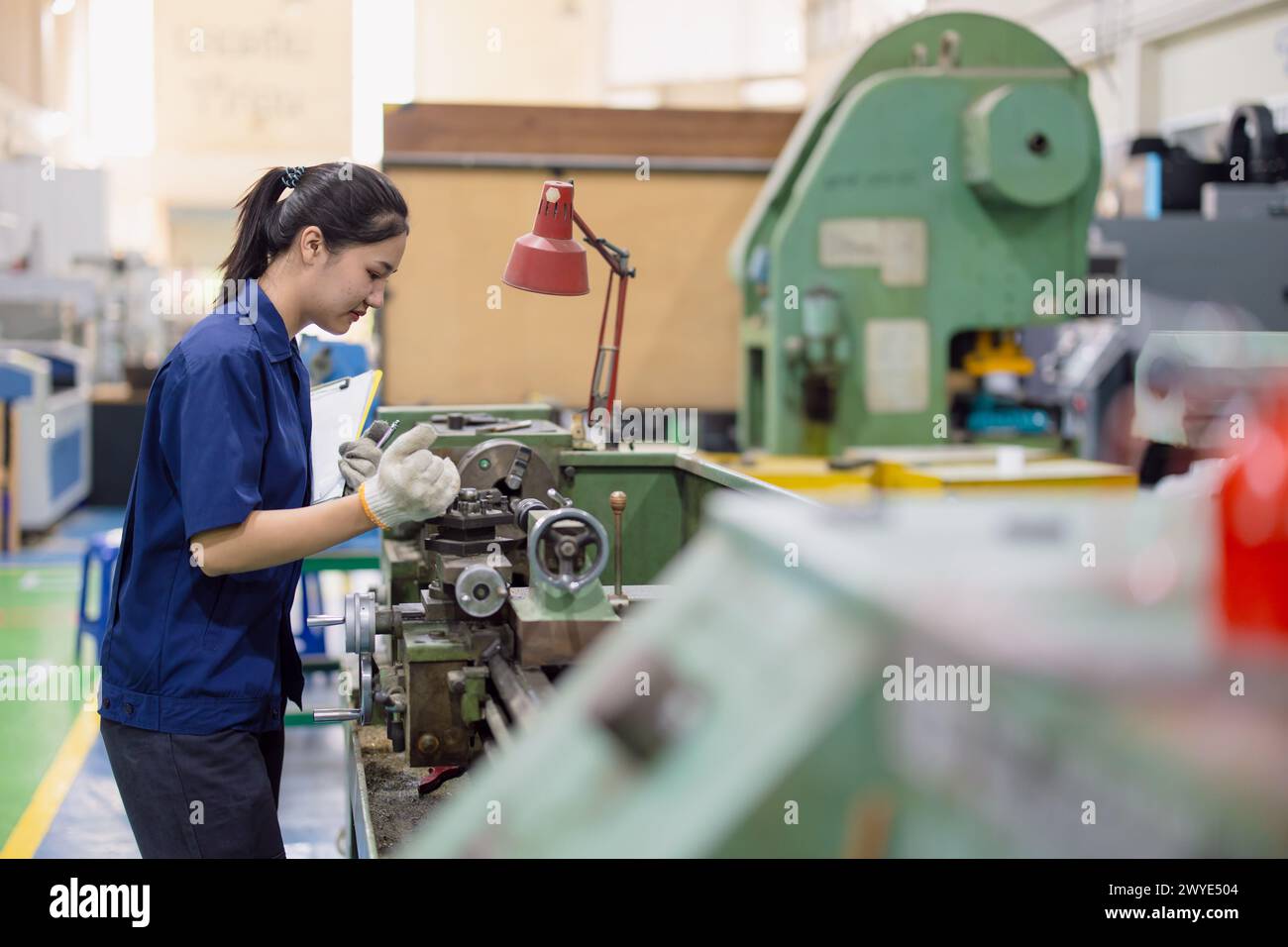 Asiatische Arbeiterinnen arbeiten in der Schwerindustrie mit CNC-Drehmaschine Fräsen Metallmaschine in Stahlproduktfabrik Stockfoto
