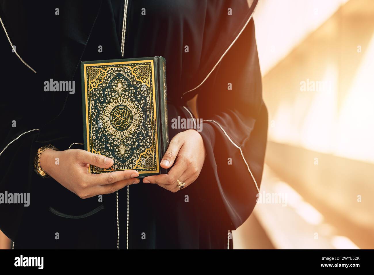 Heiliger Koranbucheinband mit arabischer Kalligraphie übersetzen die Bedeutung des Al-Koran. Die Hand der Araber hält ein muslimisches Koran-Buch. Stockfoto