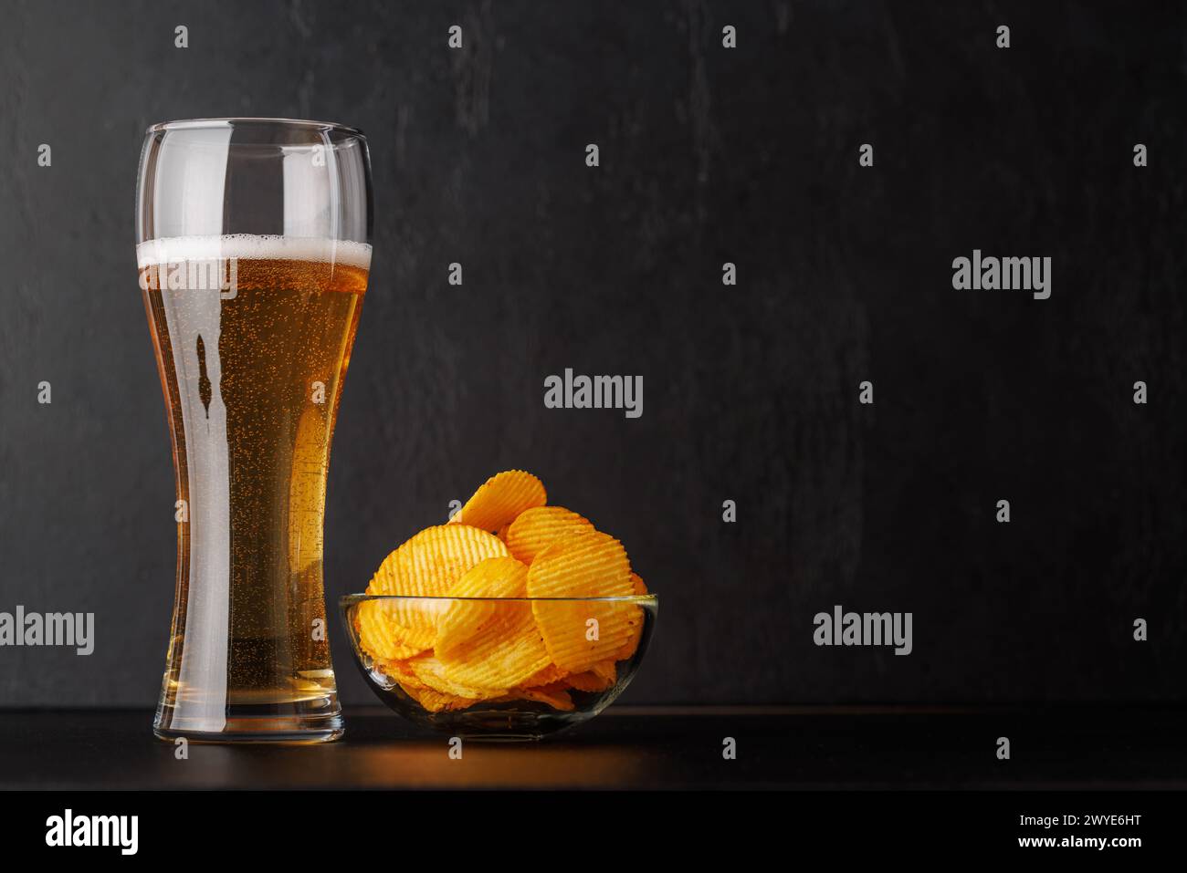Bier und Kartoffelchips. Über dunklem Hintergrund mit Kopierraum Stockfoto