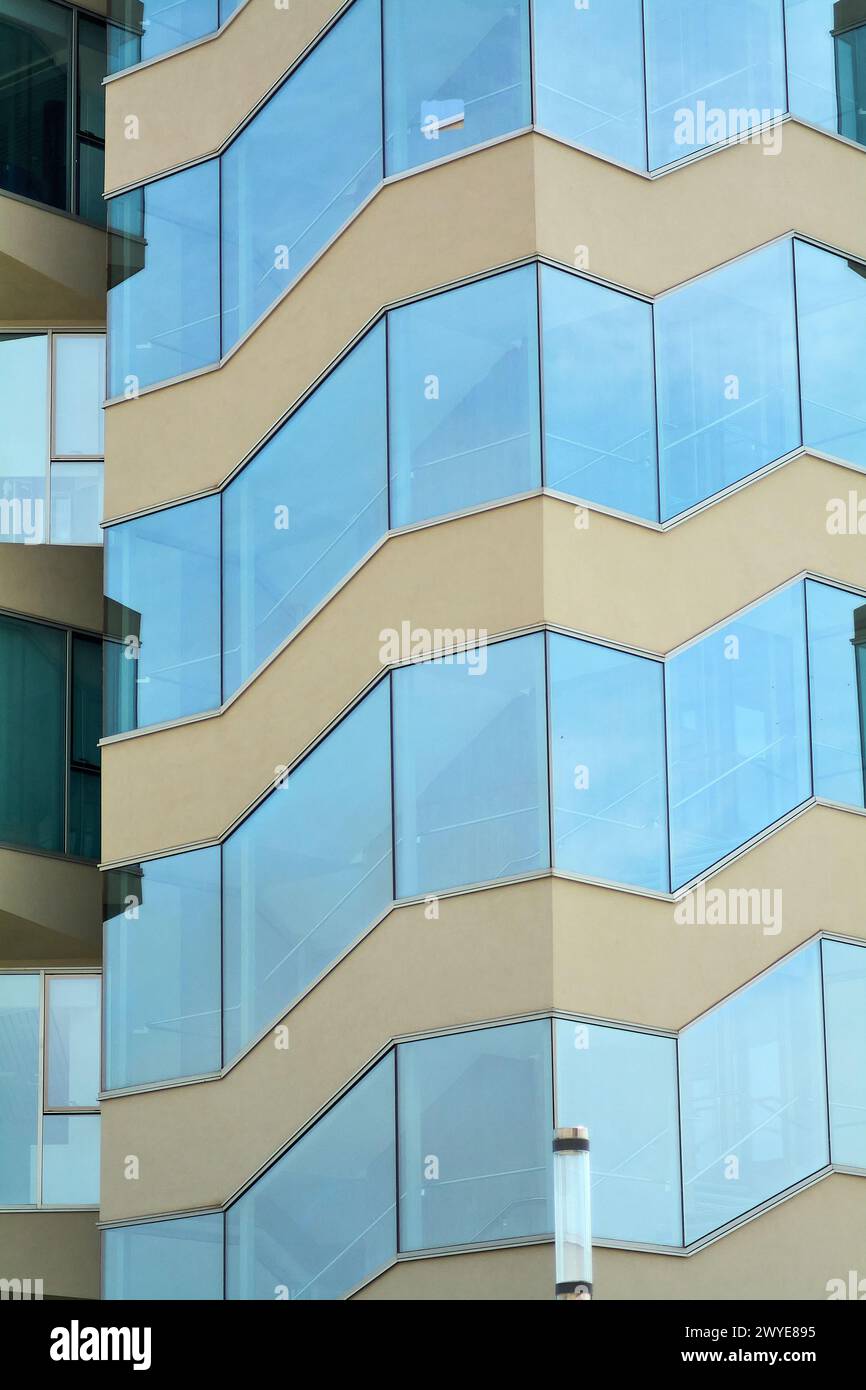 Gebäudefassade in Katalonien mit eckigem Design und Glaselementen, die natürliches Licht reflektieren und die zeitgenössische architektonische Ästhetik hervorheben. Stockfoto