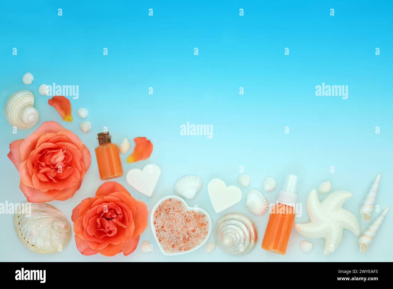 Schönheitsbehandlungen mit Rosenblüten, Orangenflora, Salzen, Duschgel, Seife und dekorativen Muscheln auf blauem Farbverlauf. Werkseitig. Stockfoto
