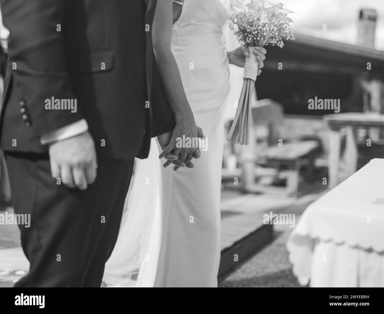 Bräutigam und Braut halten an ihrem Hochzeitstag Hände vor dem ersten Kuss, Schwarzweißfoto Stockfoto