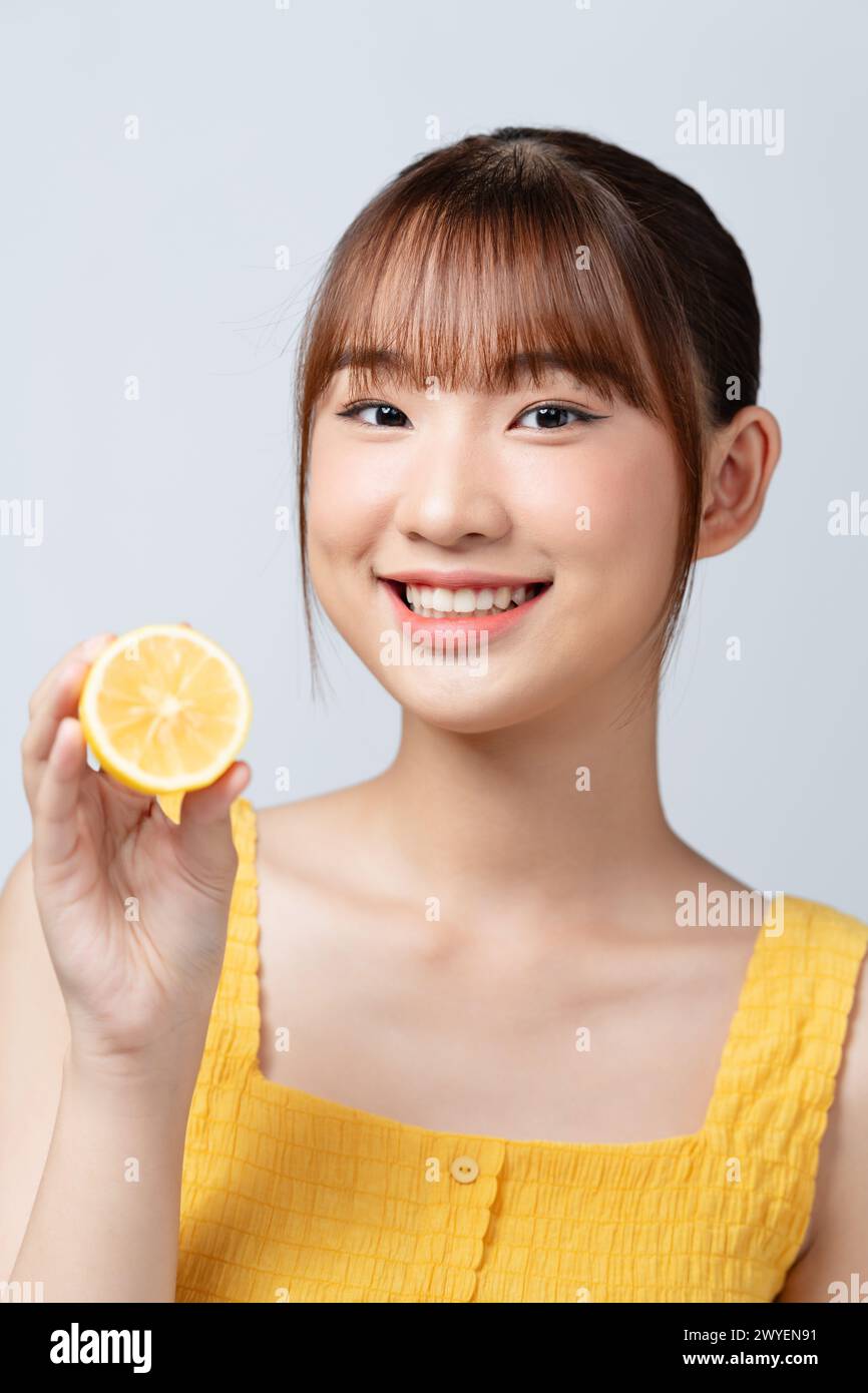 Asiatische Frau halten eine halbe Zitrone Vitamine Gesundheit Kosmetologie weißen Hintergrund Stockfoto