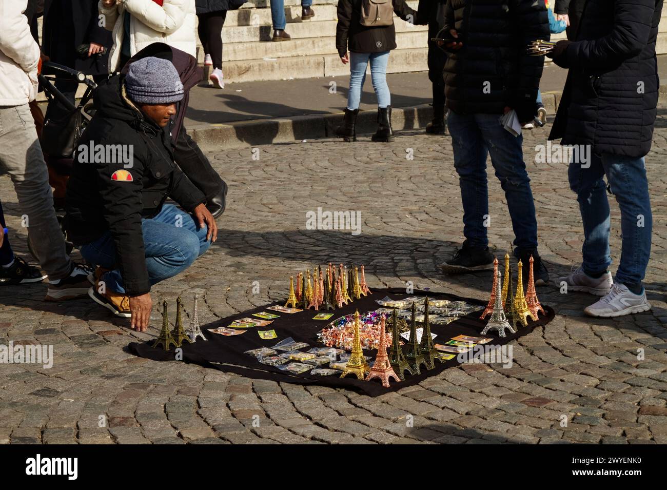 Straßenverkäufer mit Miniatur-Eiffeltürmen und Vorhängeschlössern auf Einem Blatt zum Verkauf auf den Kopfsteinpflastern vor der Sacre Coeur, Paris, Frankreich Stockfoto