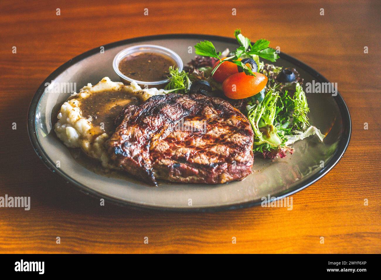 Ribeye-Steak mit Kartoffelpüree und Soße, Mesclun-Salat und Pilzsauce Stockfoto