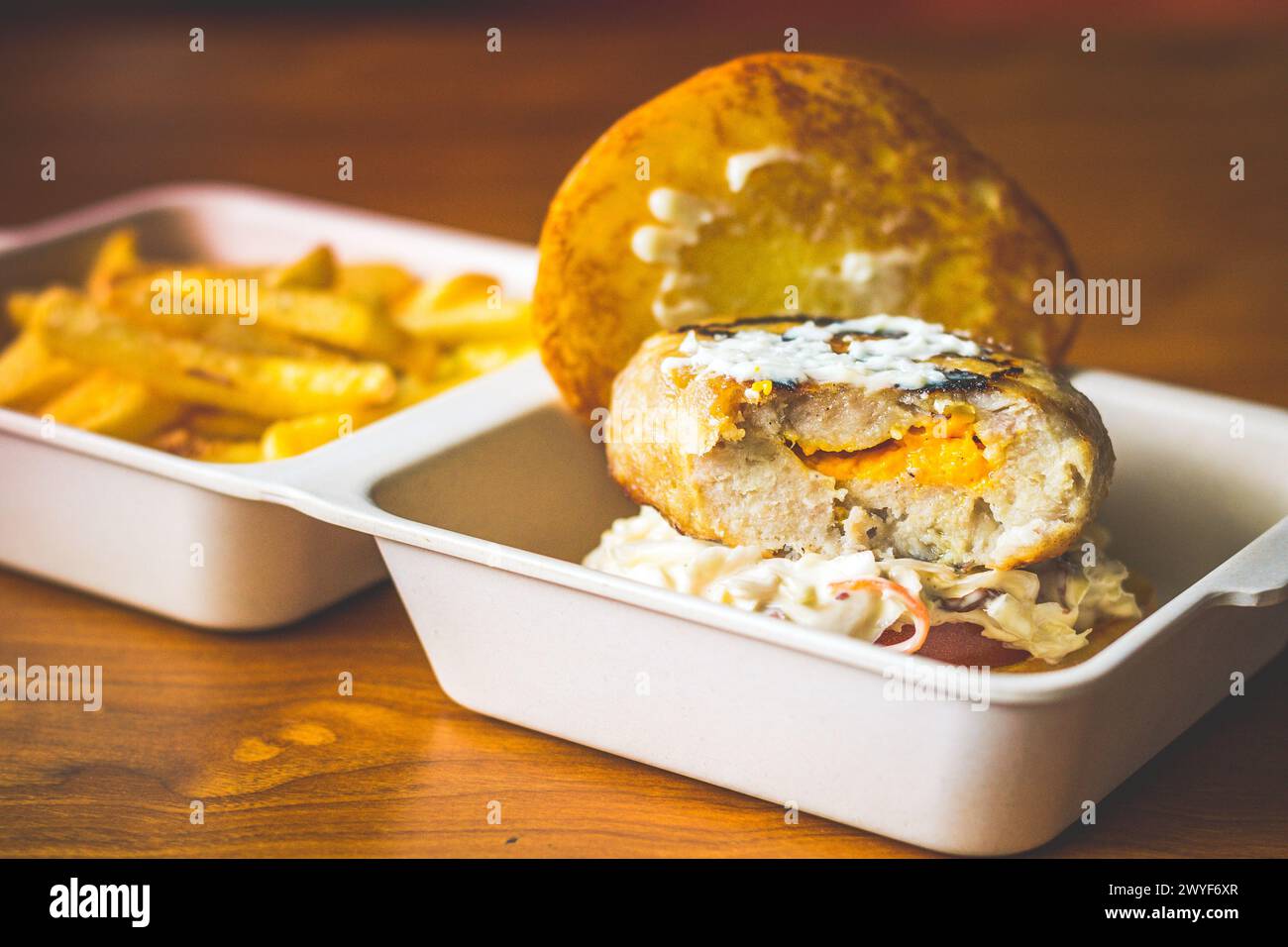 Mit Käse gefüllter Schweinefleisch-Burger mit Käsesalat und Pommes frites Stockfoto