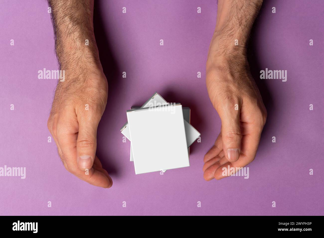 Männliche Hände um Pillen-Kisten vor violettem Hintergrund, Auswahlpfad inbegriffen. Stockfoto