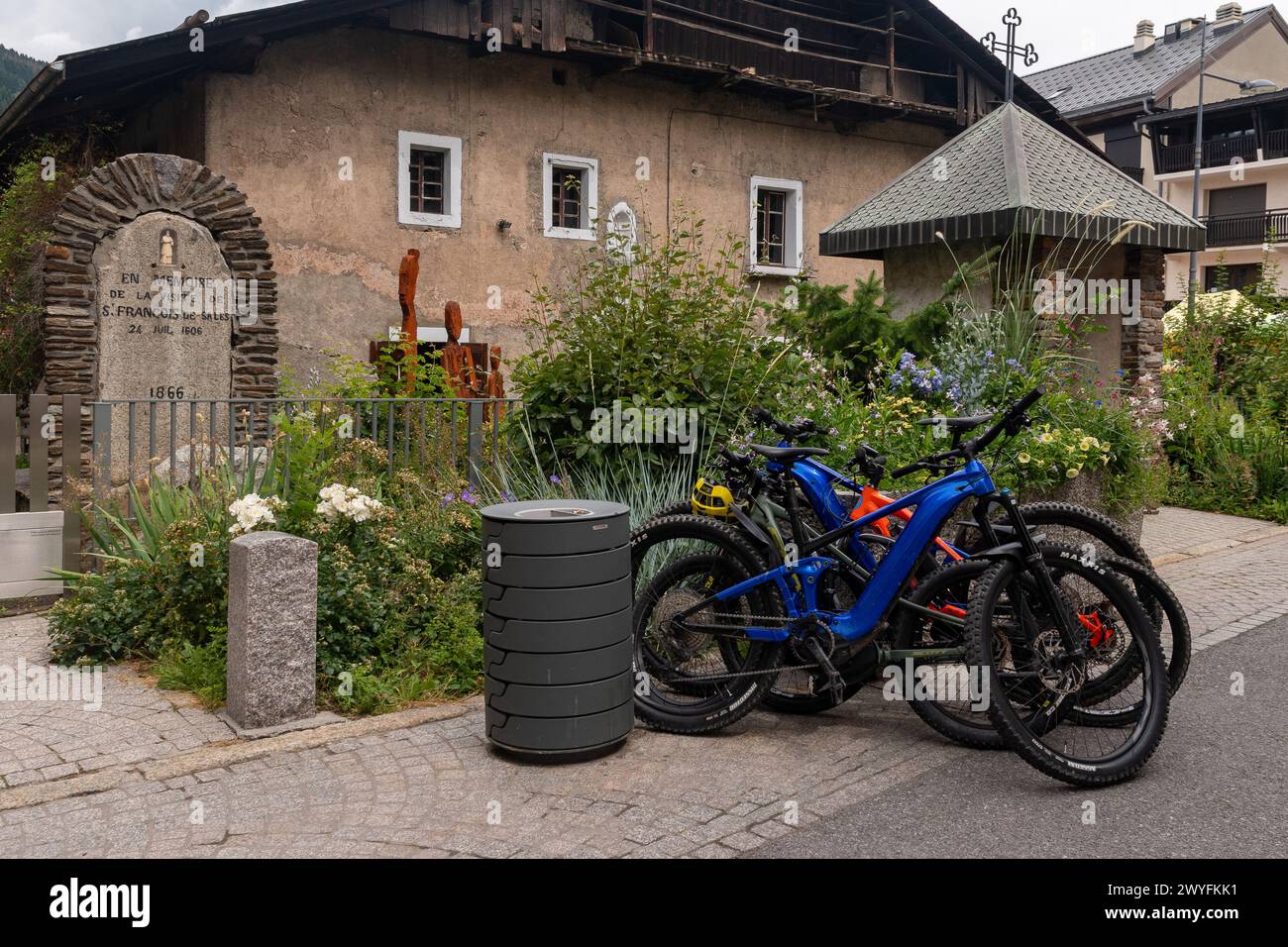 Mountainbikes parken vor einem Gedenkstein, der an den Passieren des Heiligen Francis de Sales (1567–1622) in der Bergstadt Megeve, Frankreich, erinnert Stockfoto