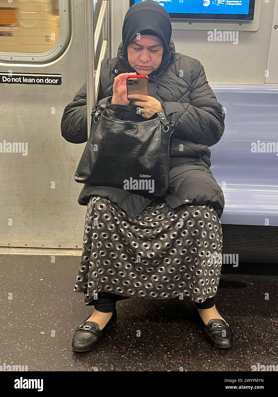 Frau, die in Brooklyn, New York, mit ihrem Smartphone unterwegs war. Stockfoto