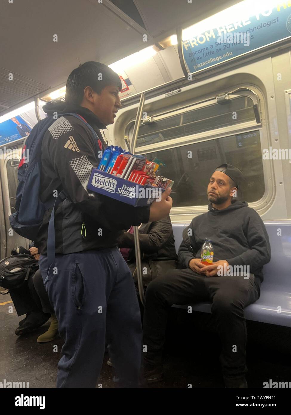 Ein nicht englischsprachiger Immigrant verkauft Süßigkeiten in einer U-Bahn, die versucht, ein paar Dollar in Brooklyn, New York, zu verdienen. Stockfoto