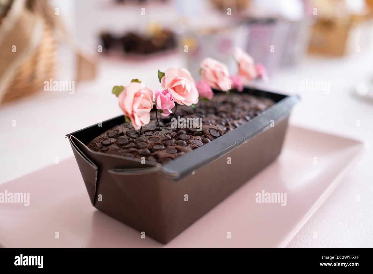 Detail eines Schokoladenkuchens mit Schokoladenchips. Es ist ein Osterbonbon-Tisch mit der typischen Osterhasen-Dekoration, Eiern und Süßigkeiten. Stockfoto