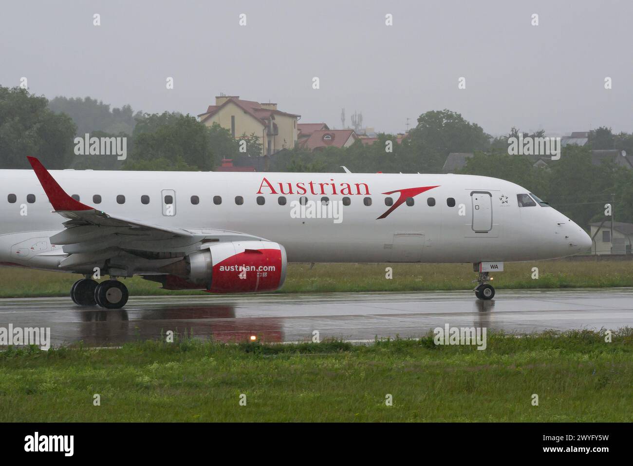 Nahaufnahme eines Embraer E195-Flugzeugs der Austrian Airlines, das bei Regen zur Landebahn für den Start vom Flughafen Lemberg fährt Stockfoto