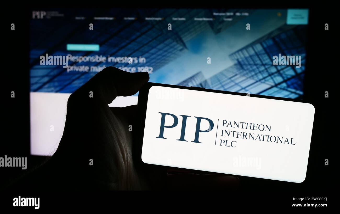 Person, die ein Mobiltelefon mit dem Logo des britischen Unternehmens Pantheon International plc (PIP) vor der Business-Webseite hält. Schwerpunkt auf dem Display des Telefons. Stockfoto
