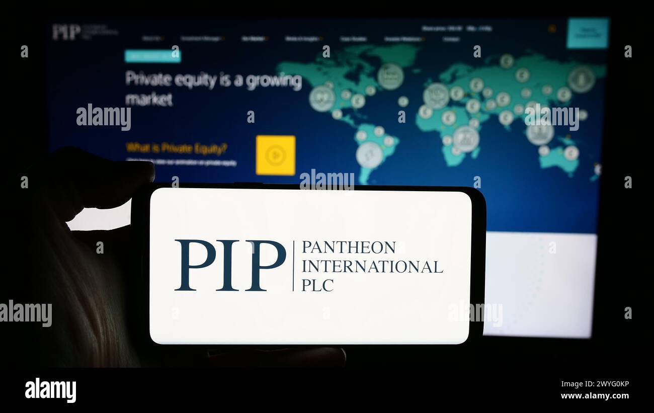 Person, die ein Mobiltelefon mit dem Logo des britischen Unternehmens Pantheon International plc (PIP) vor der Website des Unternehmens hält. Schwerpunkt auf dem Display des Telefons. Stockfoto