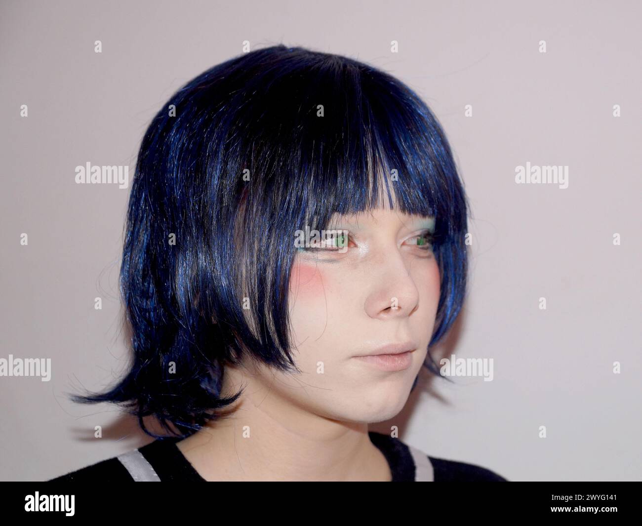 Porträt eines traurigen Teenagers im Anime-Stil mit blauen Haaren und grünen Augen, Seitenansicht Stockfoto
