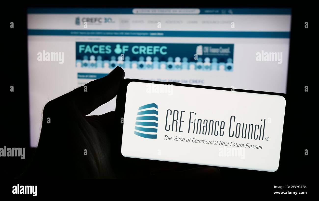 Person mit Smartphone und Logo des Wirtschaftsverbandes CRE Finance Council (CREFC) vor der Website. Schwerpunkt auf dem Display des Telefons. Stockfoto