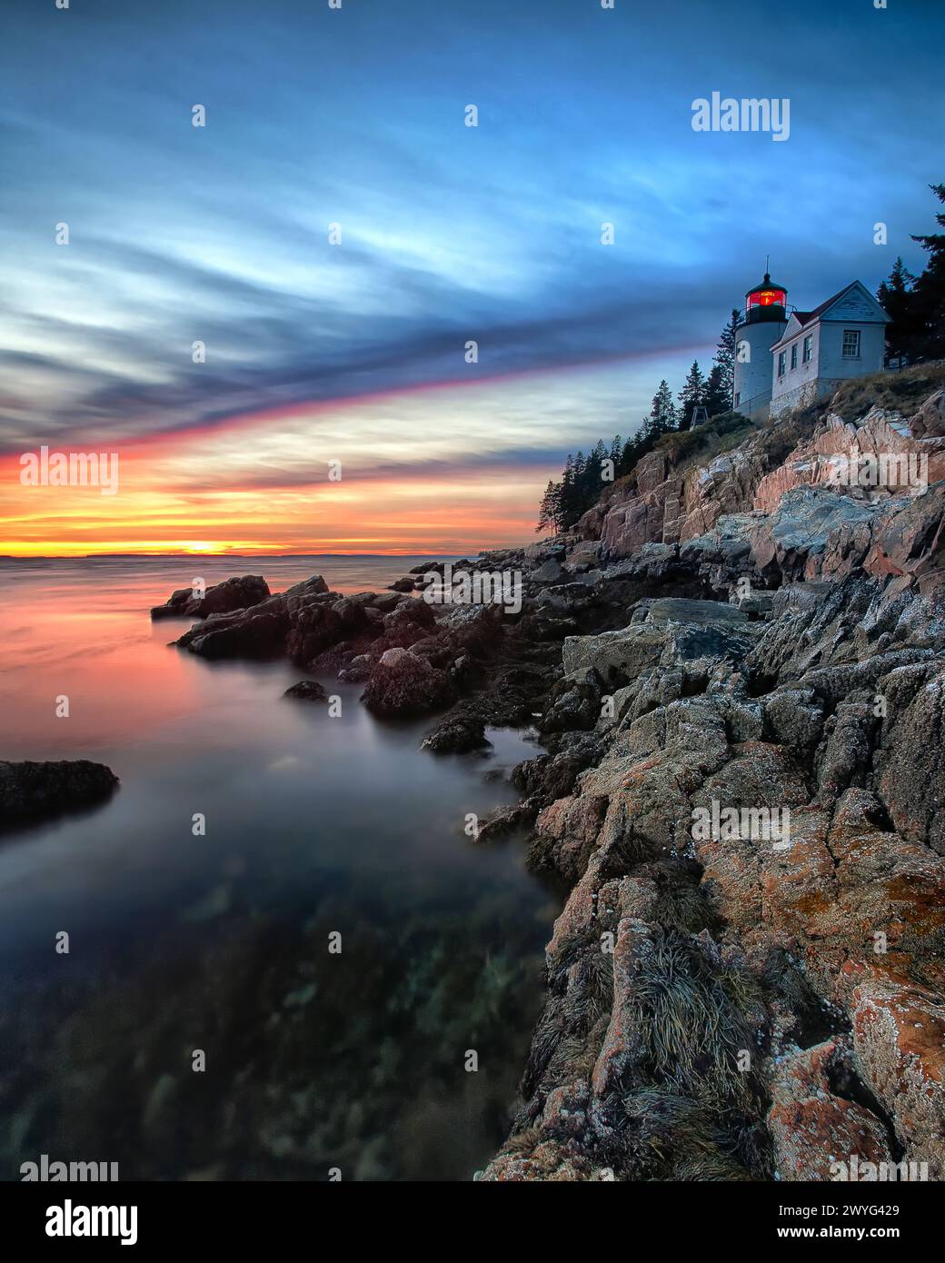 Vertikale Ansicht eines Leuchtturms auf einer Klippe bei Sonnenuntergang, Bass Harbor Head Lighthouse, Maine Stockfoto
