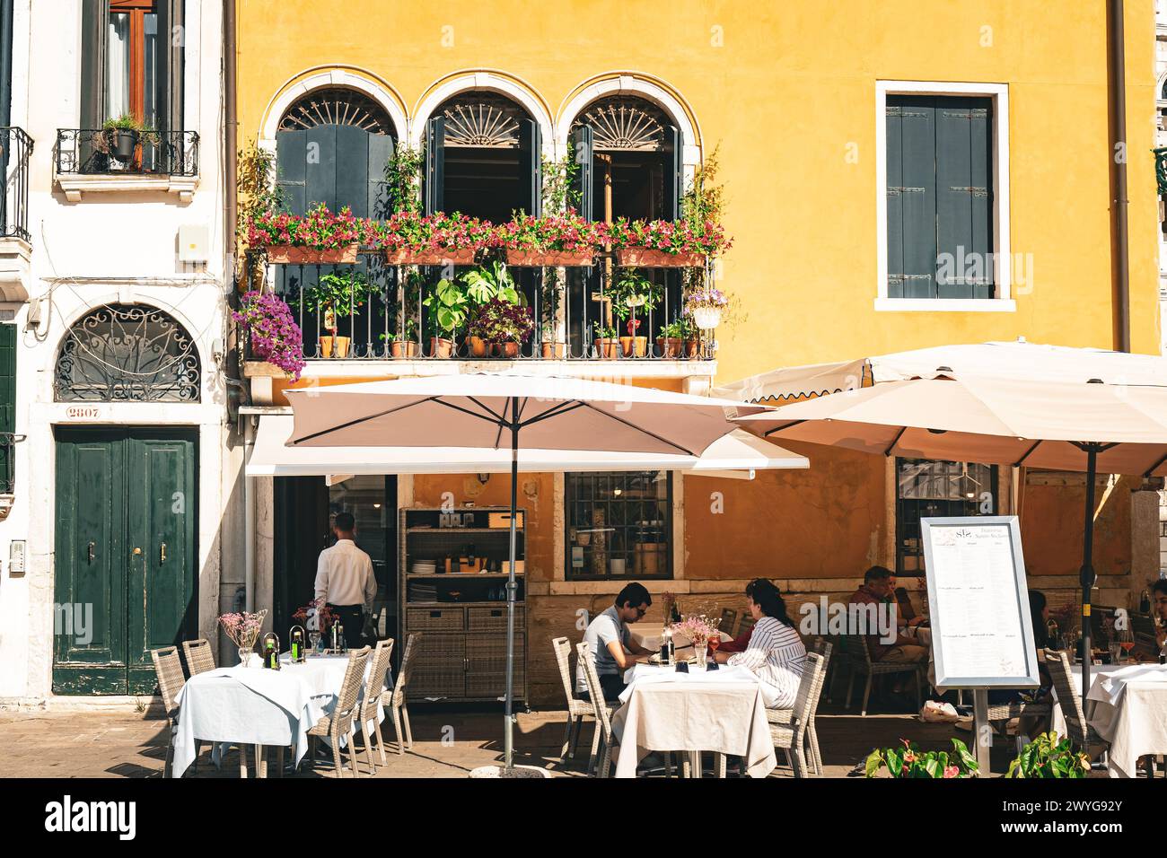 Venedig, Italien - 14. August 2023: Restauranttische und -Stühle auf einem kleinen Platz in Venedig, Italien Stockfoto